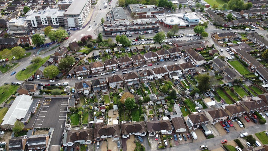 Aerial black-and-white photograph of a densely built residential area featuring numerous small houses and terraced rows, with narrow, winding streets and alleyways connecting properties. The rooftops 